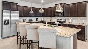 A modern kitchen with dark wood cabinets, stainless steel appliances, and a granite countertop. - Windsor Island Resort 10 Bedroom Luxury Villa 2031 10 Villa (Davenport)