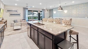 A modern kitchen with a large island, dark cabinetry, and pendant lighting. - Windsor Island Resort 10 Bedroom Luxury Villa 2031 10 Villa (Davenport)