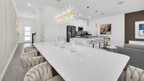 A modern kitchen with a large island, white cabinetry, and a chandelier. - Luxury 4 Bedroom Storey Lake Townhome 2444Reading 4 Townhouse (Kissimmee)