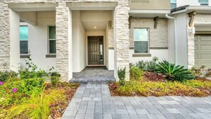 A modern house with a stone facade, a front porch, and a well-maintained garden. - Dynamic 15 Bed With Character Bedrooms Pool, Spa! 15 Villa (Kissimmee)