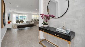 Un salon moderne avec une console noire, un miroir rond et une orchidée en pot.