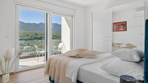 Ein Schlafzimmer mit Bett, Fenster und Bergblick.