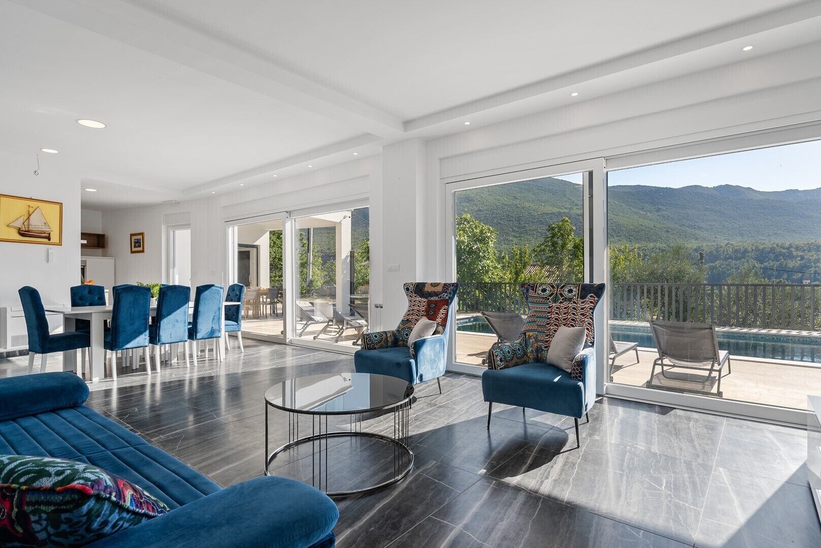 Un vaste espace de vie avec une grande porte-fenêtre coulissante donnant sur un balcon avec vue sur la piscine.