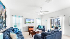 Un salon comprenant un ensemble de canapés, une table basse, un téléviseur et un ventilateur de plafond.