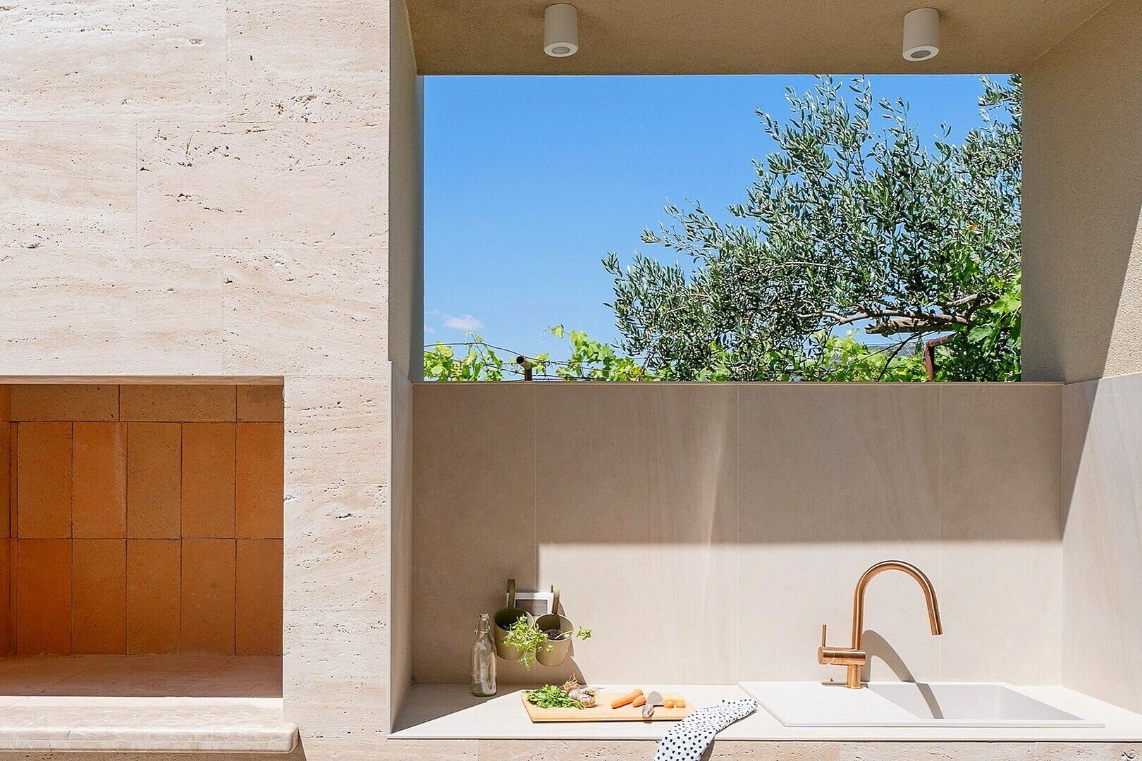 A modern bathroom with a built-in sink, a shower area, and a view of greenery.