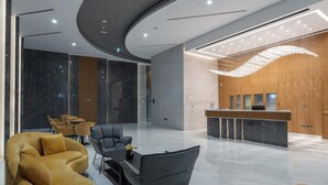 Moderni aula, jossa on vastaanottotiski, oleskelualue ja ainutlaatuinen kattovalaisin.