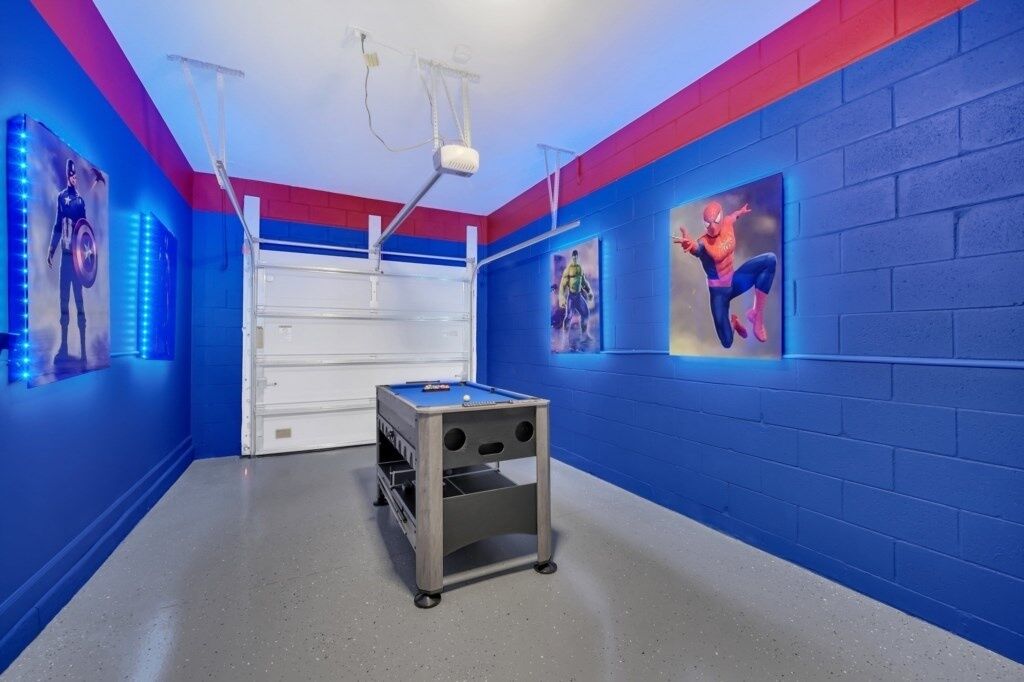 Een kamer met blauwe muren, een pooltafel en posters van superhelden.