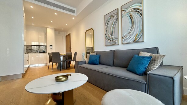 Un salon moderne avec un canapé gris, une table basse ronde et un coin repas comprenant une table et des chaises blanches.