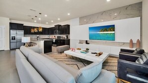 A modern living room with a grey sofa, a coffee table, and a TV mounted on the wall. - New Luxury Villa Windsor Island Resort 10beds 3616 10 Bedroom Villa (Davenport)