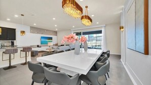 A modern kitchen with dark cabinets, a white countertop, and a large island with seating. - New Luxury Villa Windsor Island Resort 10beds 3616 10 Bedroom Villa (Davenport)