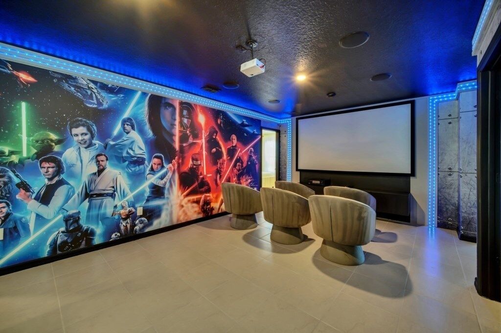 A movie theater with a Star Wars themed wall, comfortable seating, and a large screen.