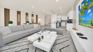 A modern living room with a grey sofa, white coffee table, and a painting of a beach scene. - 4297lana 8 Bedroom Villa (Davenport)