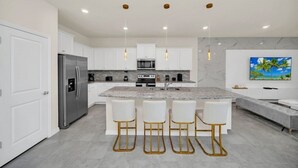 A modern kitchen with white cabinetry, a central island with bar stools, stainless steel appliances, and pendant lighting. - 4297lana 8 Bedroom Villa (Davenport)