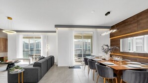 Ein moderner Essbereich mit einem Holztisch, gedeckten Plätzen für sechs Personen, grauen Polsterstühlen und einem großen Fenster mit Blick auf die Stadtlandschaft.