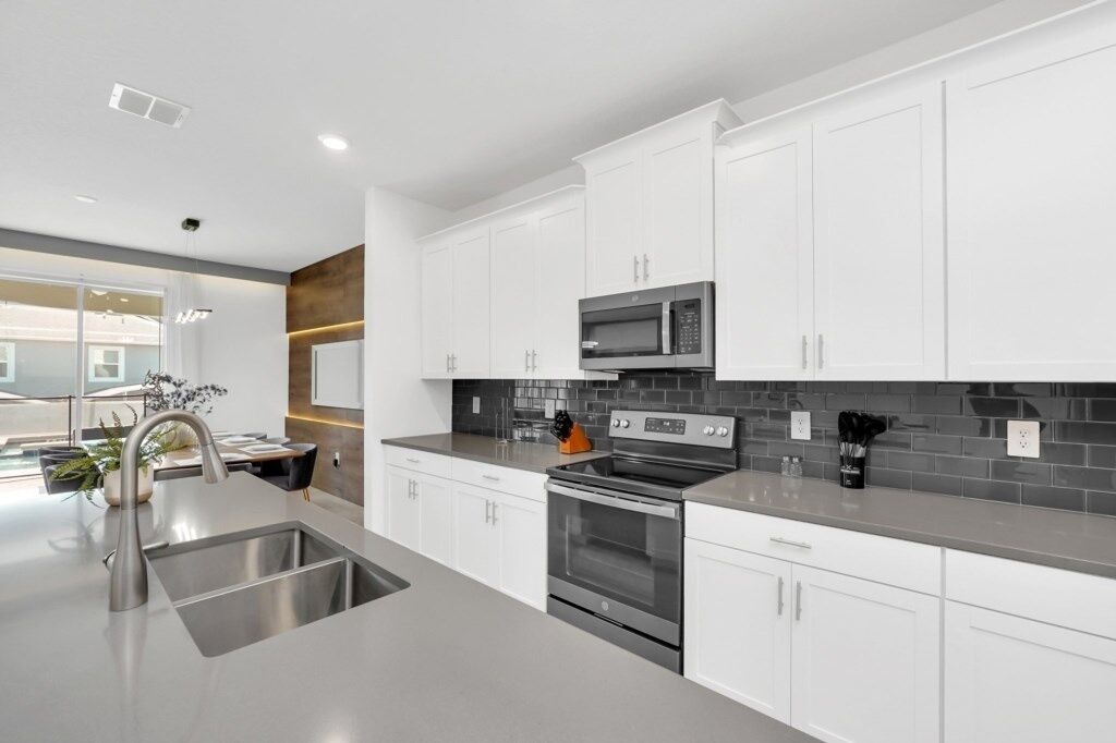 A modern kitchen with white cabinets, stainless steel appliances, and a grey countertop.