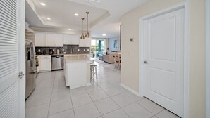A modern kitchen with white cabinets, a central island, and pendant lighting.