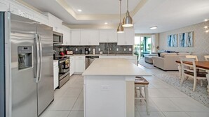 A modern kitchen with a central island, stainless steel appliances, and white cabinetry.