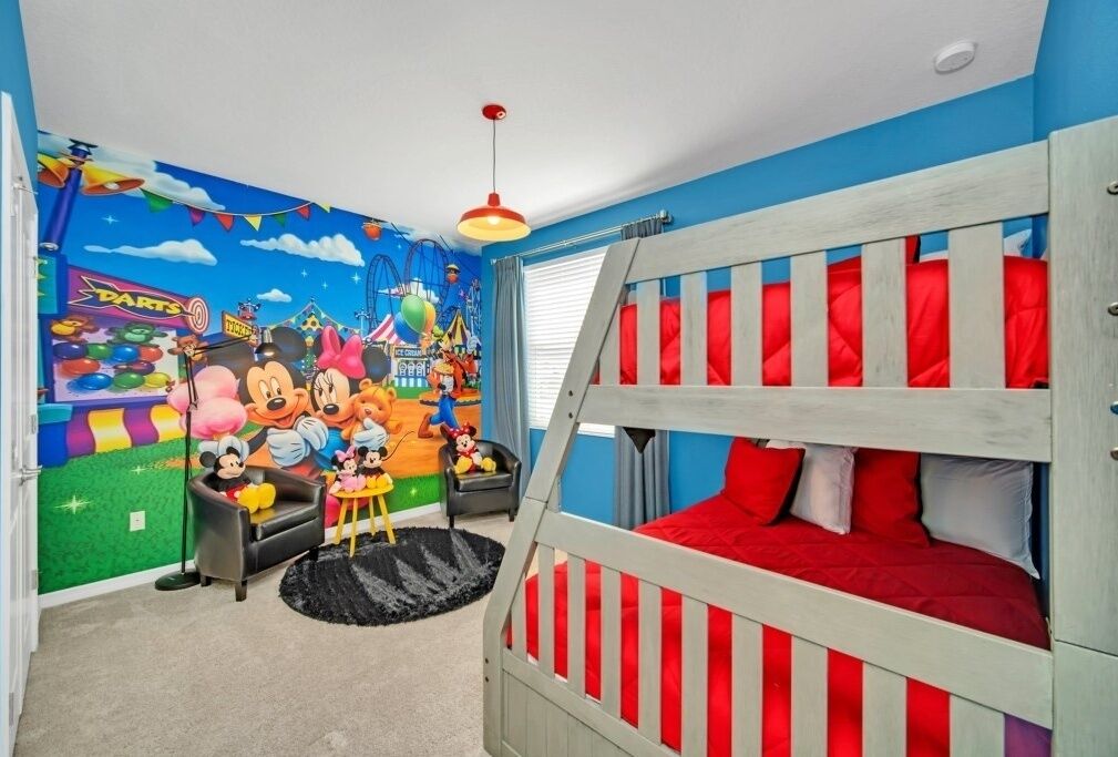 Une chambre d’enfant avec un lit superposé, une fresque représentant des personnages de dessins animés et un petit espace de jeux.