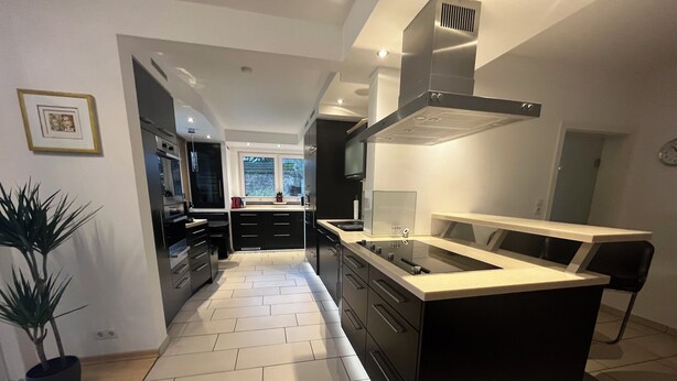 Een moderne keuken met een centraal eiland, zwarte kastjes en een groot raam.