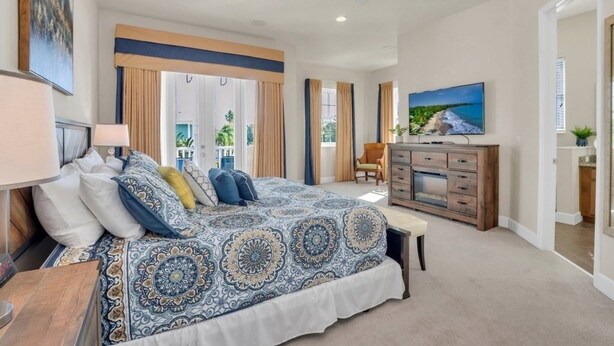 A bedroom with a large bed, a ceiling fan, a TV, and a view of the outdoors. - Amazing Reunion Resort 1421fair 5 Bedroom Villa (Kissimmee)