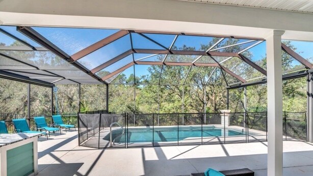 A covered outdoor swimming pool area with lounge chairs and a glass enclosure. - Amazing Reunion Resort 1421fair 5 Bedroom Villa (Kissimmee)