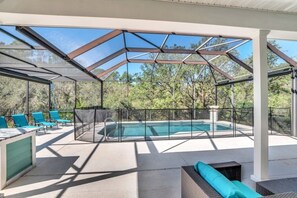 A covered outdoor swimming pool area with lounge chairs and a glass enclosure. - Amazing Reunion Resort 1421fair 5 Bedroom Villa (Kissimmee)