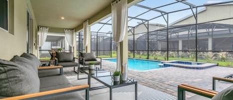 A covered outdoor area with a pool, seating, and a greenhouse structure.
