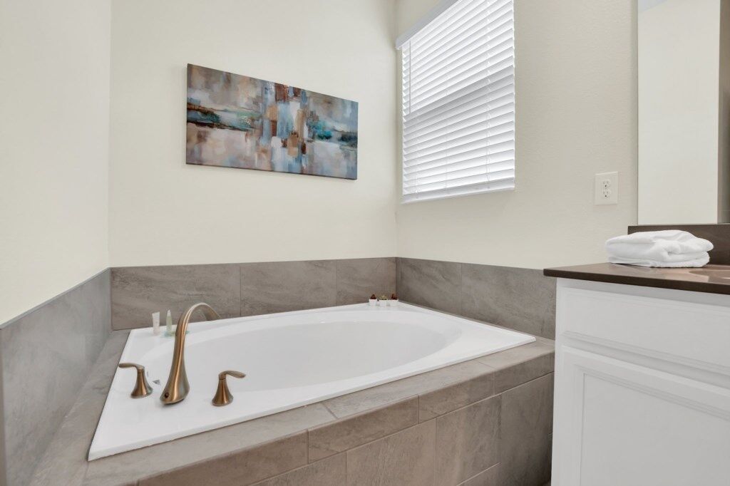 A modern bathroom with a freestanding bathtub, a large mirror, and a contemporary abstract painting on the wall.