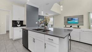 A modern kitchen with white cabinetry, a central island, and pendant lighting.