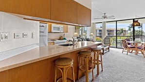 A modern kitchen with a large island, bar stools, and a view of the outdoors. - Maui Sunset A412 1 Bedroom Condo (Kihei)
