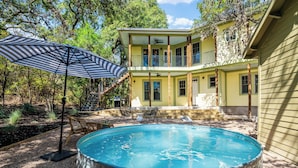 Una casa a due piani con piscina, mobili da esterno e una veranda coperta.