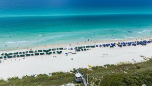 Une plage aux eaux turquoise et limpides, un rivage sablonneux et de nombreux parasols.