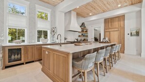 Une cuisine spacieuse dotée d’un grand îlot central, de meubles en bois et offrant une vue sur l’extérieur.