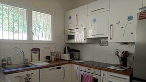 Een keuken met witte kastjes, een vaatwasser, oven, magnetron en een koelkast.