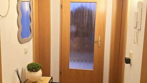 A hallway with a wooden door, a small table with a plant, and a wall-mounted light fixture. - Cozy, pet-friendly one-bedroom apartment in Meißen (Meißen)