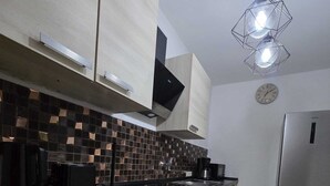 A modern kitchen with light wood cabinets, a black countertop, a tiled backsplash, and a stainless steel refrigerator. - Cozy, pet-friendly one-bedroom apartment in Meißen (Meißen)