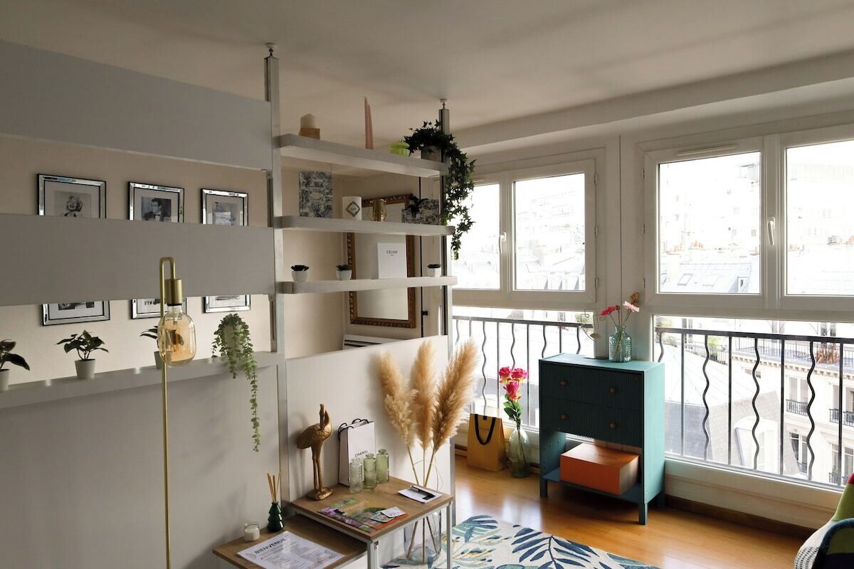 A modern living room with a wooden floor, a teal accent wall, and a balcony with a railing.