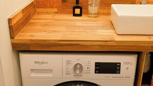 A Whirlpool washing machine under a wooden countertop with a bottle of soap and a sink.