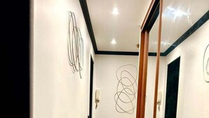 A hallway with wooden herringbone flooring, white walls, and abstract line art.
