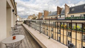 Un balcó amb taula i caires, amb vista a una filera d'edificis de diversos estils arquitectònics.