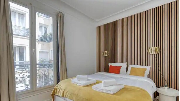 Ein Hotelzimmer mit einem großen Bett, einem Fenster mit Vorhängen, einer gestreiften Wand und einem kleinen Nachttisch.