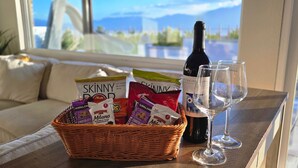 En fletkurv fyldt med snacks, en vinflaske og to glas på et bord på en balkon.