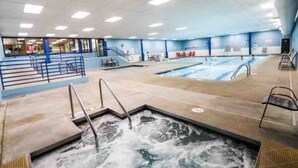 A large indoor swimming pool with multiple lanes, a separate hot tub area, and a viewing area with a railing. - Waterfront Boho Retreat (Wisconsin Dells)