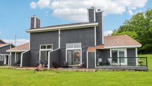 A modern two-story house with a large front porch, a garage, and a well-maintained lawn. - Waterfront Boho Retreat (Wisconsin Dells)