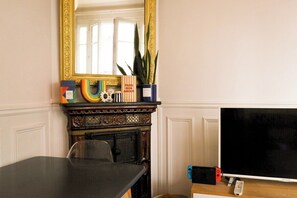 Cozy room with a traditional fireplace, flat-screen TV, and a wooden table.