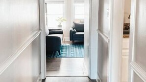 A hallway with wooden flooring leading to a living area with a sofa and a rug. - High Tide at CB - 75 steps to Beach Access (Carolina Beach)