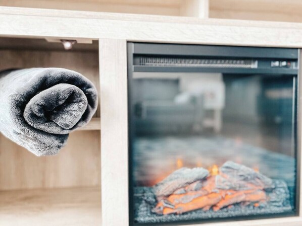 A room with a fireplace, a rolled-up towel, and a window with a view of the outside.