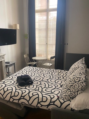 Une chambre d’hôtel avec un lit, une télévision, un bureau et une chaise.