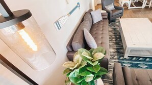 Een woonkamer met een bank, een salontafel, een plant in pot en een eethoek met een tafel en stoelen.