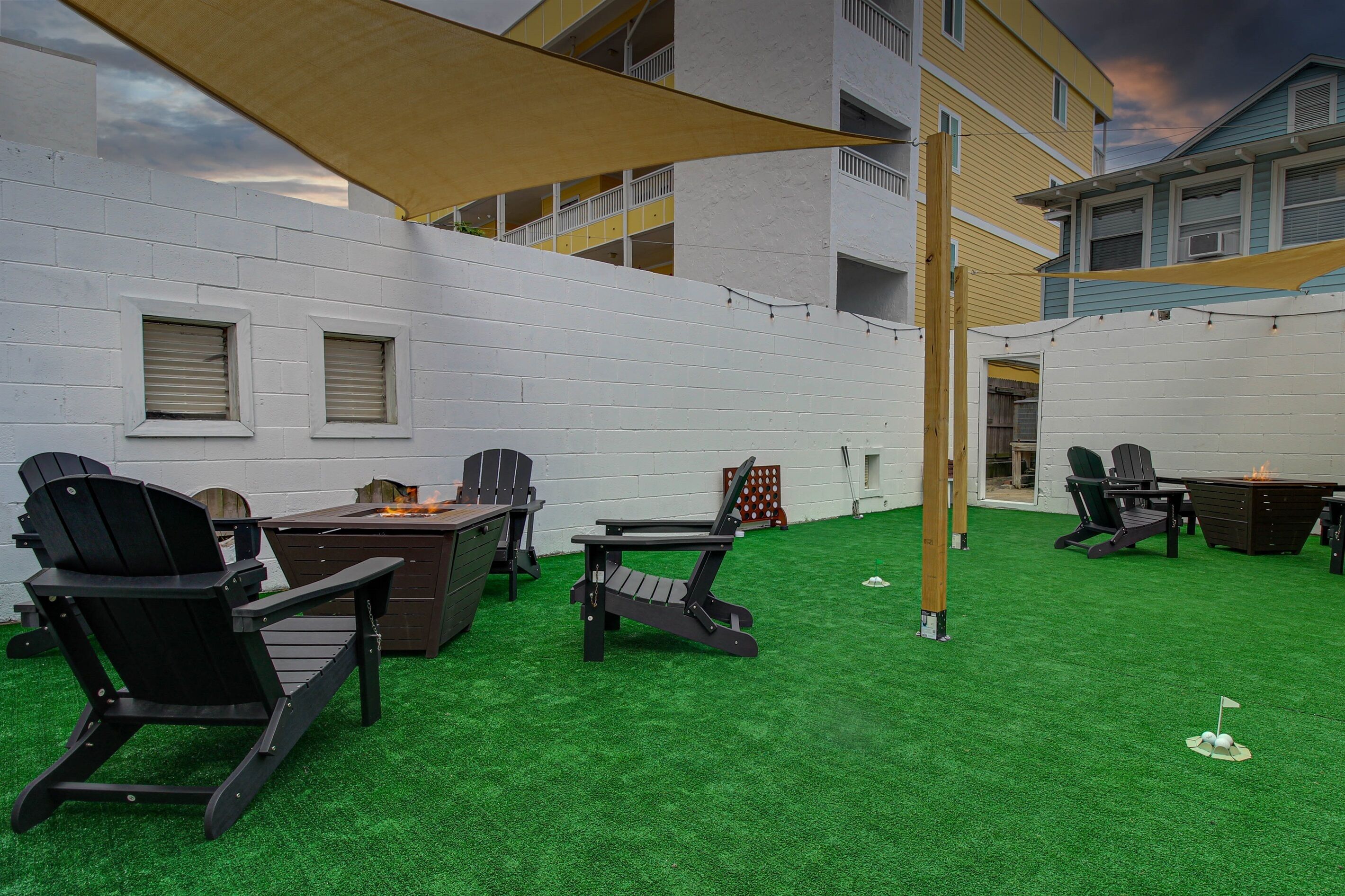 Un patio al aire libre con césped artificial, mobiliario exterior y un gran paraguas que proporciona sombra.
